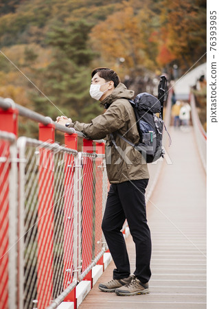 Asian handsome man with mask trekking, climbing autumn mountain Asian handsome man with mask trekking, climbing autumn mountain 76393985