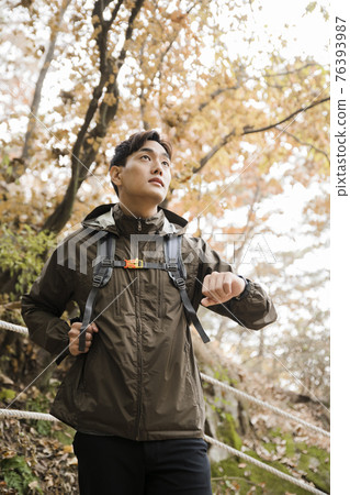 Asian handsome man trekking, climbing autumn mountain Asian handsome man trekking, climbing autumn mountain 76393987