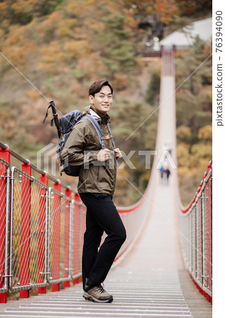 Asian handsome man with mask trekking, climbing autumn mountain Asian handsome man with mask trekking, climbing autumn mountain 76394090