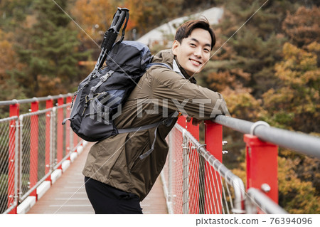 Asian handsome man with mask trekking, climbing autumn mountain Asian handsome man with mask trekking, climbing autumn mountain 76394096