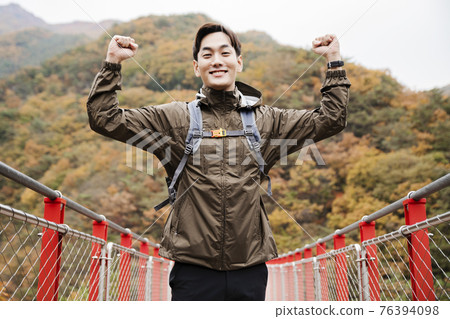 Asian handsome man with mask trekking, climbing autumn mountain Asian handsome man with mask trekking, climbing autumn mountain 76394098
