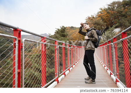 Asian handsome man with mask trekking, climbing autumn mountain Asian handsome man with mask trekking, climbing autumn mountain 76394114