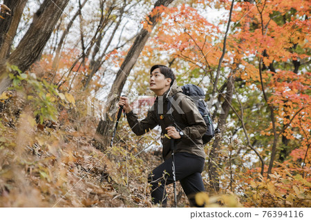 Asian handsome man trekking, climbing autumn mountain Asian handsome man trekking, climbing autumn mountain 76394116