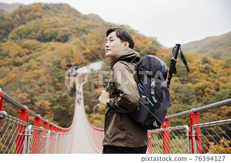 Asian handsome man with mask trekking, climbing autumn mountain Asian handsome man with mask trekking, climbing autumn mountain 76394127