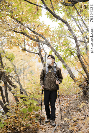 Asian handsome man with mask trekking, climbing autumn mountain 76394128