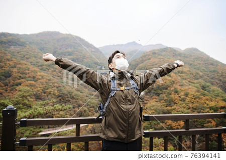 Asian handsome man with mask trekking, climbing autumn mountain Asian handsome man with mask trekking, climbing autumn mountain 76394141
