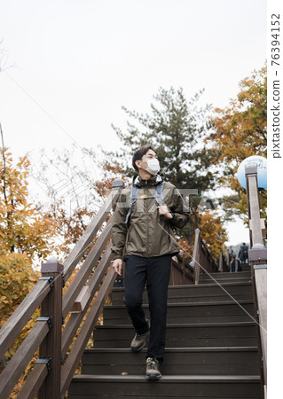 Asian handsome man with mask trekking, climbing autumn mountain 76394152