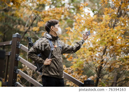 Asian handsome man with mask trekking, climbing autumn mountain Asian handsome man with mask trekking, climbing autumn mountain 76394163