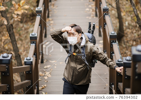 Asian handsome man with mask trekking, climbing autumn mountain Asian handsome man with mask trekking, climbing autumn mountain 76394302