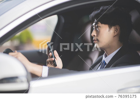 angry Asian male in suit using mobile phone in the car angry Asian male in suit using mobile phone in the car 76395175