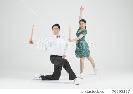 Asian couple contemporary dancers holding bread roller Asian couple contemporary dancers holding bread roller 76395357