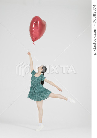 Asian female contemporary dancer making move with heart balloon Asian female contemporary dancer making move with heart balloon 76395374