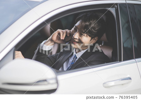 angry Asian male in suit using mobile phone in the car angry Asian male in suit using mobile phone in the car 76395405