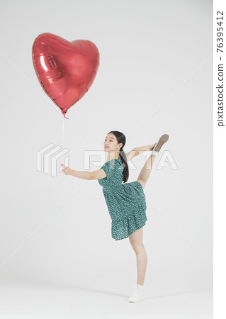 Asian female contemporary dancer making move with heart balloon Asian female contemporary dancer making move with heart balloon 76395412