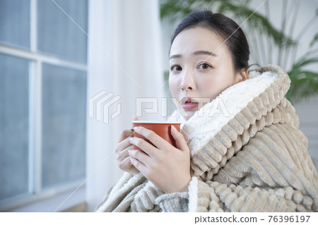 Asian woman drinking hot coffee or tea in blankets Asian woman drinking hot coffee or tea in blankets 76396197