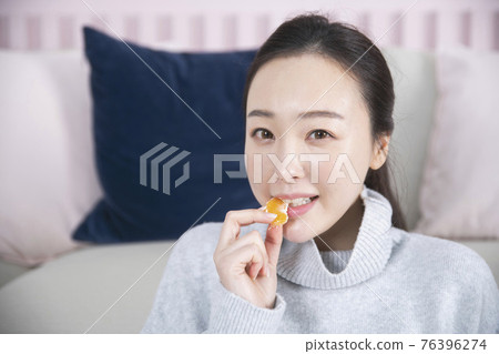 Asian single solo woman living alone concept eating tangerine Asian single solo woman living alone concept eating tangerine 76396274