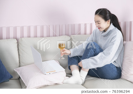 single solo woman living alone concept video chat with beer 76396294