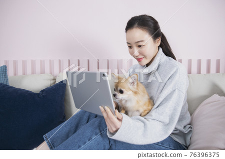 Asian single solo woman enjoying home alone time concept using tablet with pet dog Asian single solo woman enjoying home alone time concept using tablet with pet dog 76396375