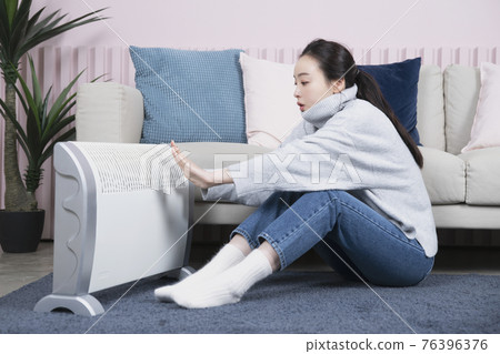 Asian single solo woman living alone concept using electric heater in winter Asian single solo woman living alone concept using electric heater in winter 76396376