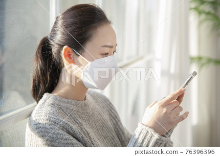 Asian woman wearing mask using smart phone Asian woman wearing mask using smart phone 76396396