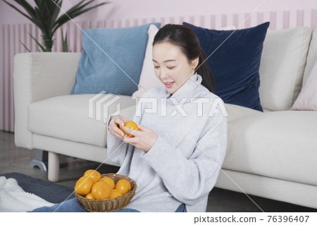 Asian single solo woman living alone concept eating tangerine 76396407