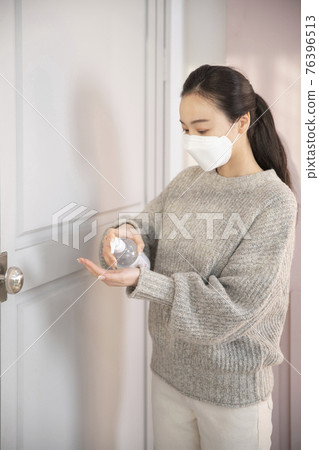 Asian woman wearing mask using hand sanitizer Asian woman wearing mask using hand sanitizer 76396513