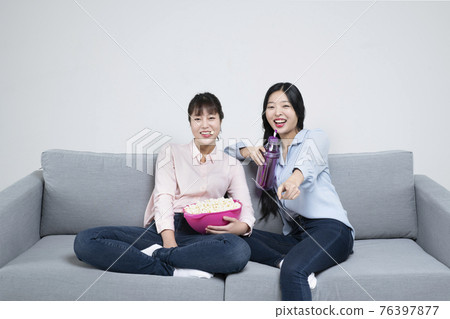 two Asian sisters, women with various facial expressions on sofa eating popcorn watching television two Asian sisters, women with various facial expressions on sofa eating popcorn watching television 76397877