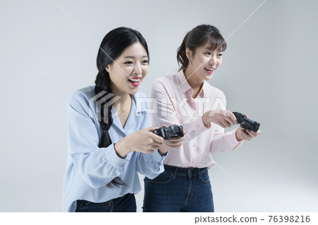 two Asian women, sisters playing video games with game controllers two Asian women, sisters playing video games with game controllers 76398216