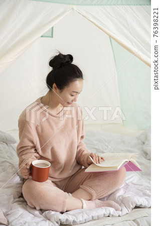 Asian woman in pajams under indoor bed tent Asian woman in pajams under indoor bed tent 76398221
