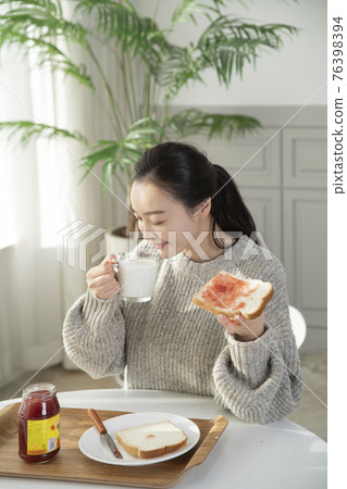 Asian woman having brunch, toast with jam at home Asian woman having brunch, toast with jam at home 76398394