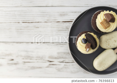 Muffins and cupcakes on tray. Cookie ice creams on a stick. Wooden background Muffins and cupcakes on tray. Cookie ice creams on a stick. Wooden background 76398813