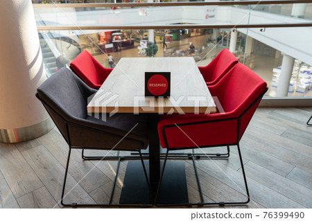 A table and soft chairs for visitors to the food court of a modern shopping center. A table and soft chairs for visitors to the food court of a modern shopping center. 76399490