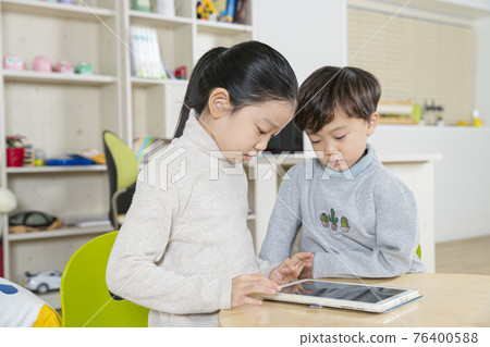 Asian girl and boy, sister and brother using tablet device Asian girl and boy, sister and brother using tablet device 76400588