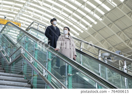 Asian man and woman with masks in escalator 76400615