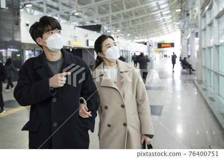 Asian couple with face masks in train station 76400751