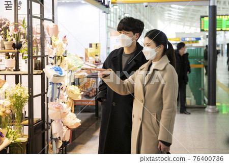 Asian couple with face masks looking at flowers 76400786