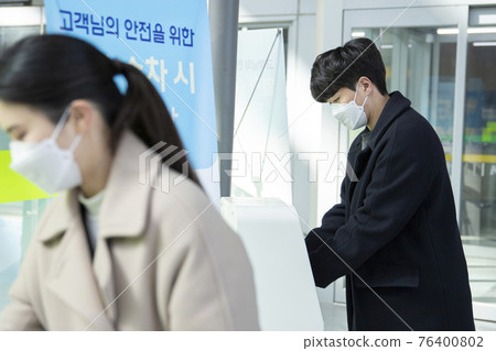 Asian man and woman sanitizing hands, train station Asian man and woman sanitizing hands, train station 76400802