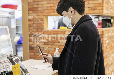 Asian man with mask scanning QR code 76400833
