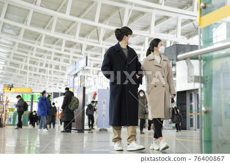 Asian couple with face masks in train station Asian couple with face masks in train station 76400867