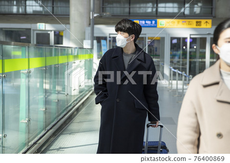 Asian man and woman with masks, carrying carrier in train station 76400869