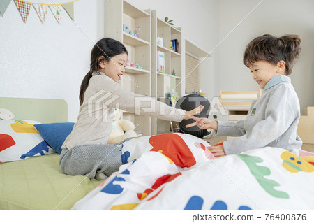 Asian girl and boy, sister and brother playing on bed Asian girl and boy, sister and brother playing on bed 76400876