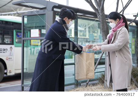 Asian woman and man with face masks handing over paper bag, face to face selling second hand stuffs concept Asian woman and man with face masks handing over paper bag, face to face selling second hand stuffs concept 76400917