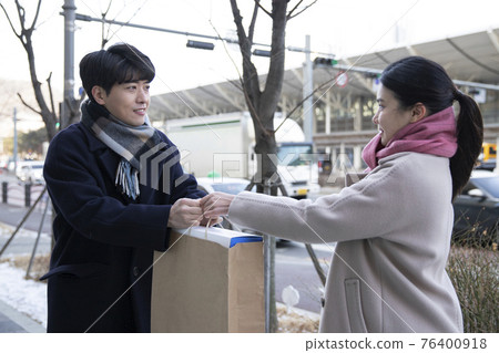 Asian woman and man handing over paper bag, face to face selling second hand stuffs concept Asian woman and man handing over paper bag, face to face selling second hand stuffs concept 76400918