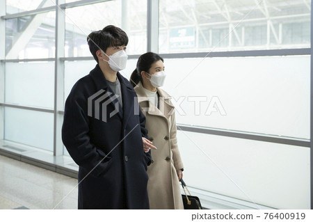 Asian couple with face masks in train station Asian couple with face masks in train station 76400919