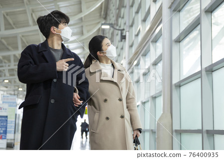 Asian couple with face masks in train station Asian couple with face masks in train station 76400935