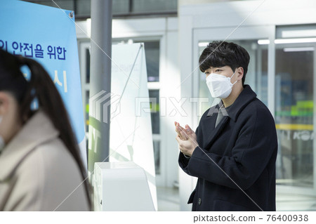 Asian man and woman sanitizing hands, train station 76400938