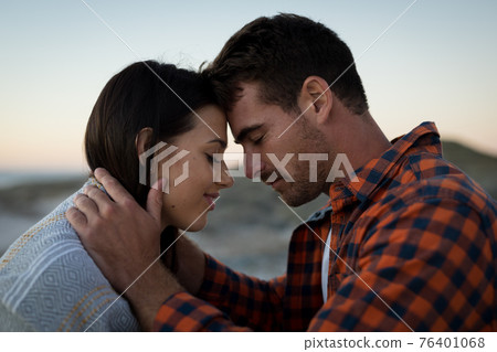 Happy caucasian couple on beach at the sea touching foreheads 76401068