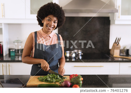 Portrait of african american woman in kitchen preparing food and smiling Portrait of african american woman in kitchen preparing food and smiling 76401276