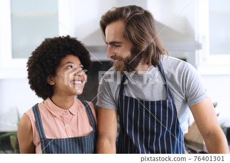 Happy diverse couple in kitchen embracing and smiling Happy diverse couple in kitchen embracing and smiling 76401301