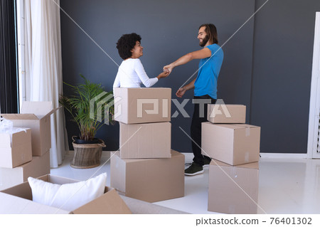 Happy diverse couple moving house smiling and dancing 76401302